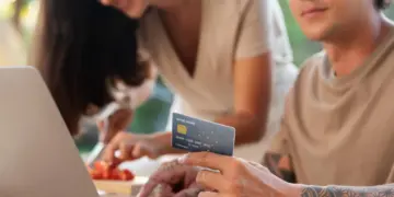 Open Finance: O que Esperar da Nova Fronteira da Conectividade Bancária? 3 Open finance: homem comprando online com cartão de crédito e mulher ao fundo