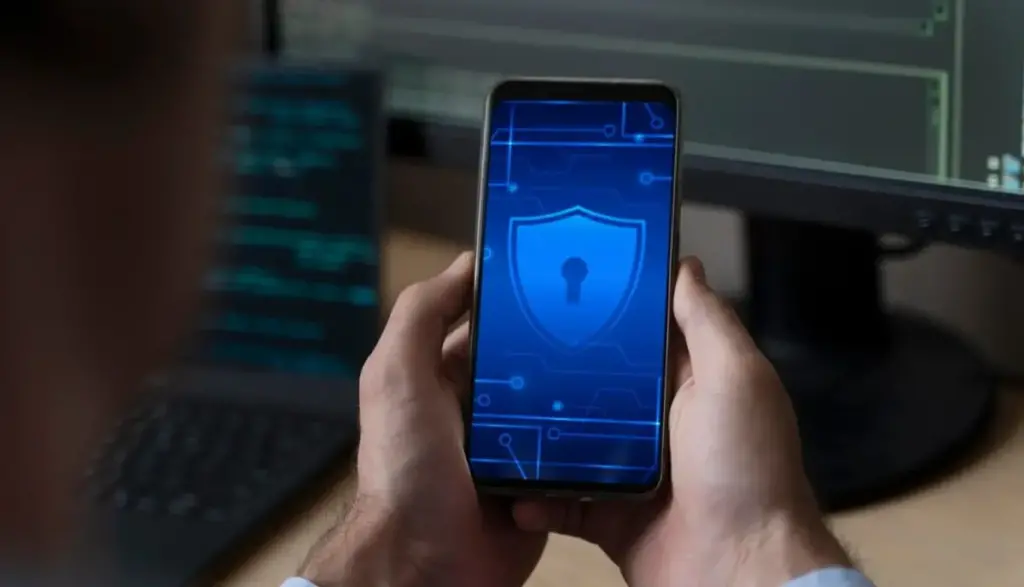 Celular com ícone de segurança digital na tela, representando aplicativos de segurança digital.