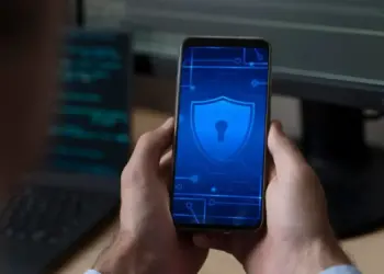 Celular com ícone de segurança digital na tela, representando aplicativos de segurança digital.