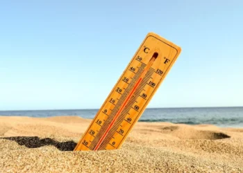 Termômetro parcialmente enterrado na areia. Falando do calor no Carnaval.