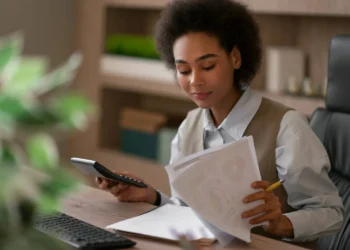 Mulher revisa cálculos e documentos sobre como declarar investimentos no exterior.