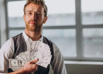 Homem segurando várias cédulas, representando sucesso na hora comprar dólar