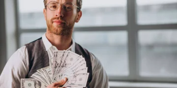 Homem segurando várias cédulas, representando sucesso na hora comprar dólar