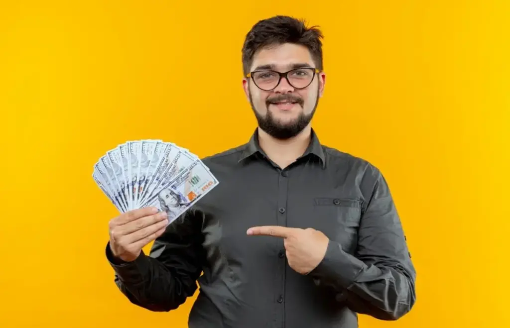 Homem aponta para cédulas, indicando ganho em dinheiro. Representando: economia compartilhada.