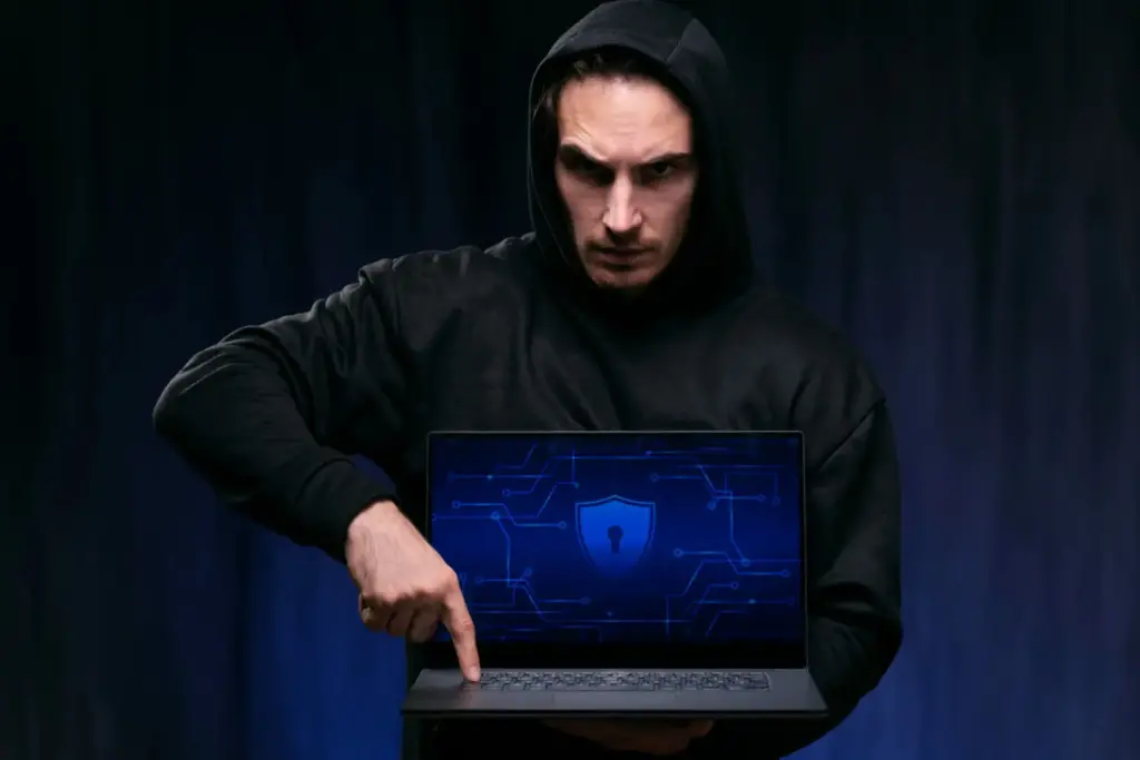 Expor seus dados na internet: homem de capuz segurando um laptop