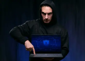 Expor seus dados na internet: homem de capuz segurando um laptop