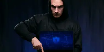 Privacidade na Internet: 6 Erros que te colocam em perigo 5 Expor seus dados na internet: homem de capuz segurando um laptop