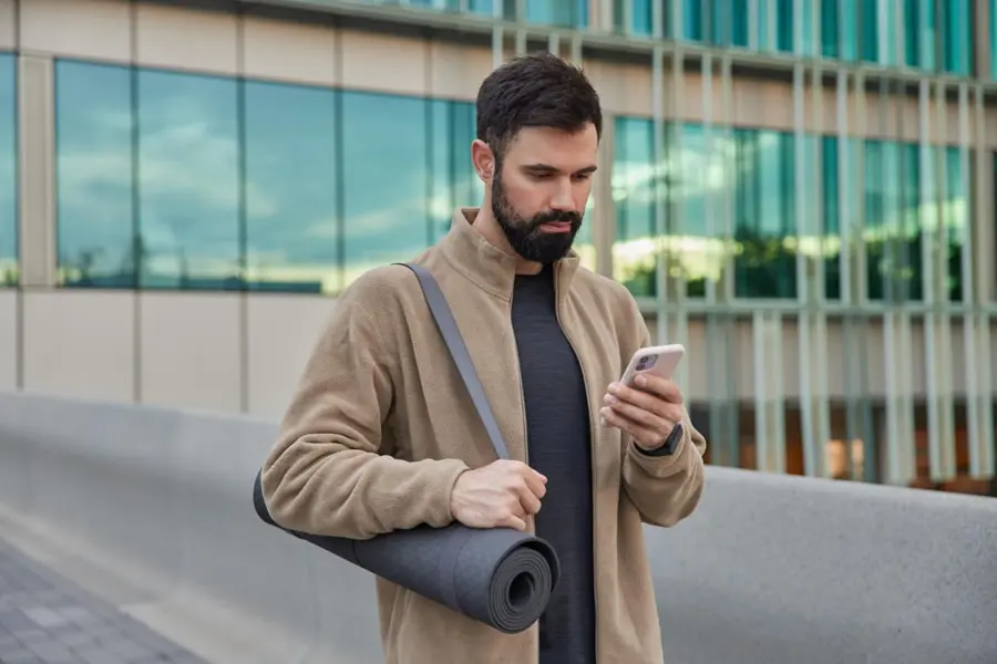 Homem utiliza o seu celular na rua, representando aplicativos de segurança digital.