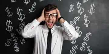 Homem com as mãos na cabeça à frente de uma quadro negro onde existem cifrões desenhados, representando golpes financeiros.