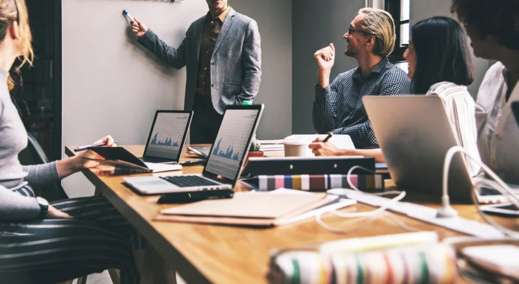 CEO lidera reunião onde apresenta dados e relatórios à sua equipe, representando hacks de produtividade.