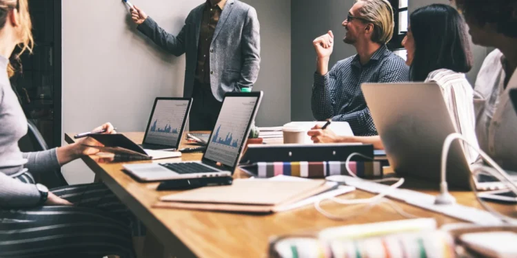 CEO lidera reunião onde apresenta dados e relatórios à sua equipe, representando hacks de produtividade.