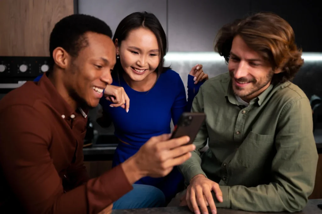 Três amigos animados olhando um iPhone 16 juntos em um ambiente aconchegante.