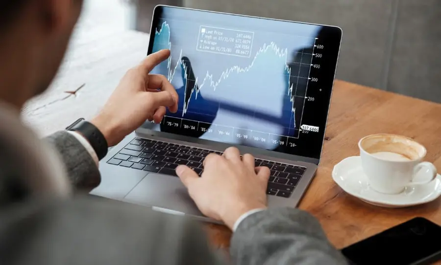 Investidor analisa gráfico em seu notebook, representando mercado cripto 2025.