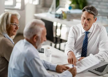Consultor explicando portabilidade de previdência privada para casal de idosos em reunião.