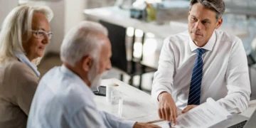 Portabilidade de Previdência Privada: Economize e Otimize Investimentos 3 Consultor explicando portabilidade de previdência privada para casal de idosos em reunião.