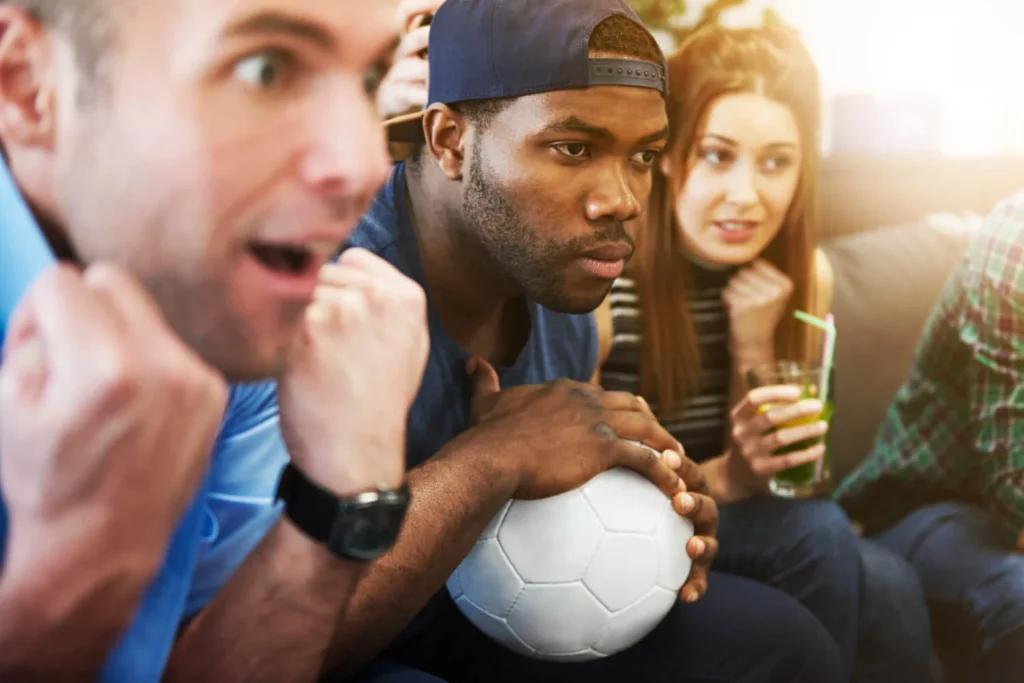 Torcedores ansiosos assistindo a um jogo, refletindo a emoção das regras de futebol.