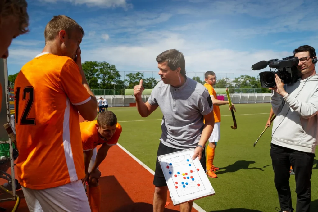 Técnico explica táticas com um quadro, ilustrando estratégias baseadas nas regras de futebol.