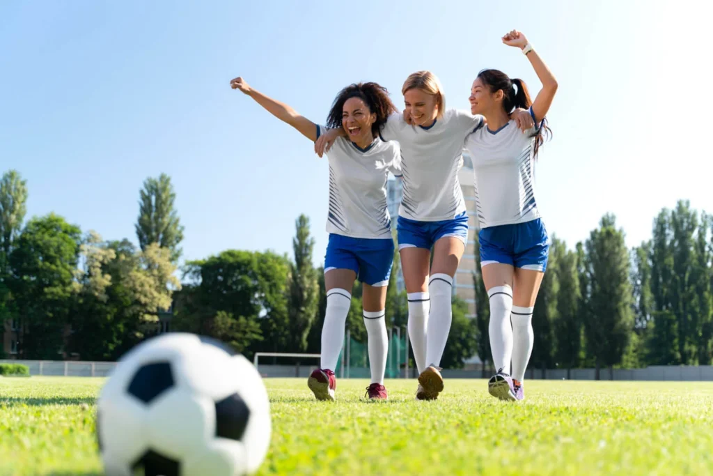 Jogadoras comemoram um gol em campo, destacando o impacto das regras de futebol.