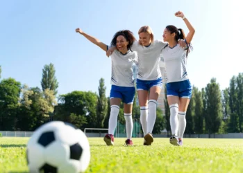 Jogadoras comemoram um gol em campo, destacando o impacto das regras de futebol.
