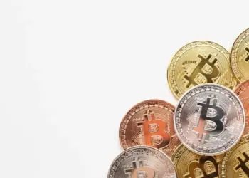 Imagem em fundo branco com algumas moedas físicas de Bitcoin, representando tendências das criptomoedas 2025.