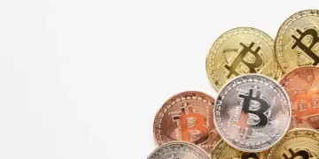 Imagem em fundo branco com algumas moedas físicas de Bitcoin, representando tendências das criptomoedas 2025.