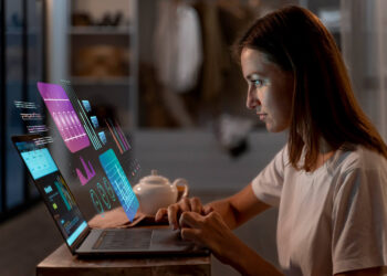 Mulher analisando gráficos digitais em um laptop, representando o uso da inteligência artificial nos negócios.