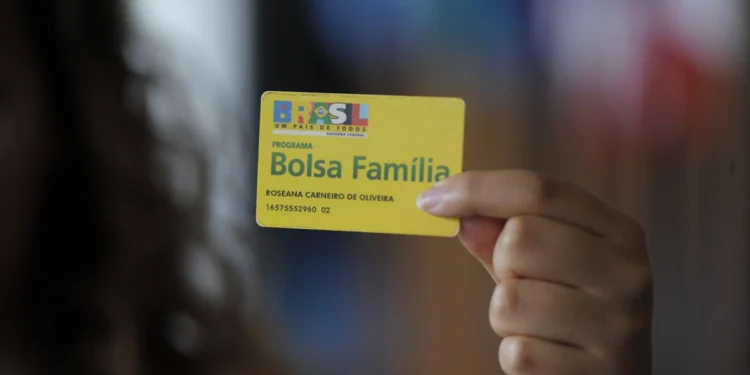 Mulher segura cartão do Bolsa Família.