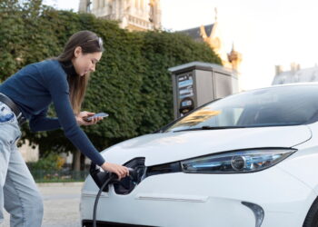 Mulher posiciona plug-in de carregamento do seu carro elétrico.