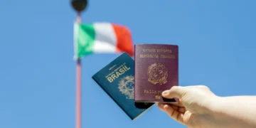 Pessoa segura um passaporte brasileiro e um italiano. Ao fundo, a bandeira da Itália tremula. Falando sobre cidadania italiana.