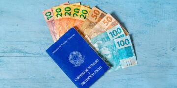 Exemplar da carteira de trabalho junto de algumas notas. Falando sobre consignado CLT para quem tem o nome sujo.