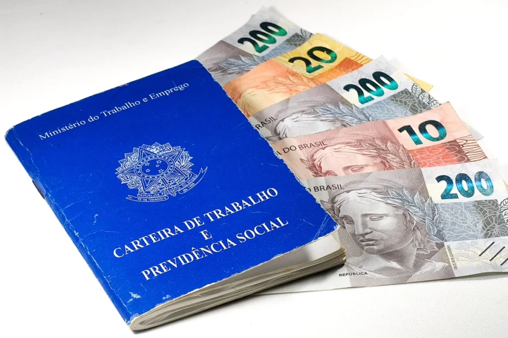 Carteira de trabalho junto a notas de R$ 200 e R$ 20. Falando de empréstimo consignado CLT.