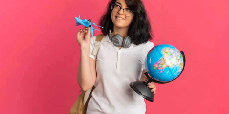 Estudar fora do Brasil: conheça os Top 7 melhores países 16 Estudante segura um globo em uma das mãos e alguns outros elementos na outra mão, todos representando o intercâmbio estudantil. Falando sobre estudar fora do Brasil.