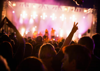 Público animado em show noturno com luzes vibrantes, representando a energia dos festivais 2025