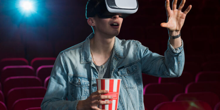Homem com óculos VR e pipoca em cinema interagindo com filmes sci-fi de forma imersiva.