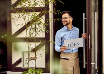 Empreendedor sorridente abre as portas de seu negócio, simbolizando o crescimento das franquias em alta.