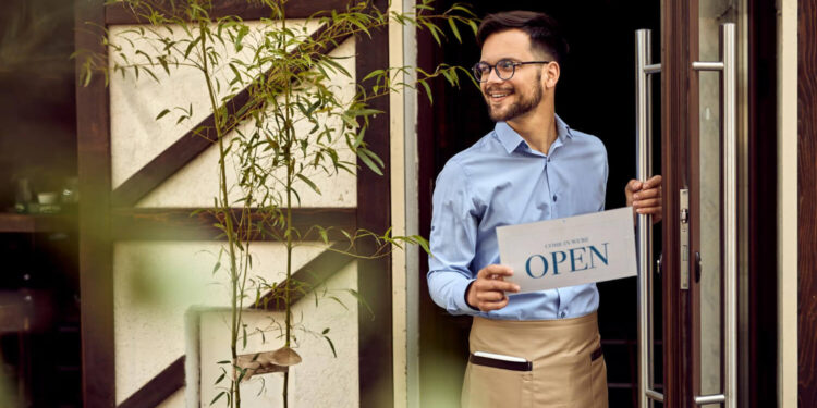 Empreendedor sorridente abre as portas de seu negócio, simbolizando o crescimento das franquias em alta.