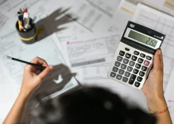 Pequeno empresário faz cálculos em meio a um processo interno de organização fiscal. Gestão fiscal em pauta.