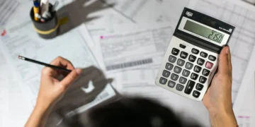 Guia completo de gestão fiscal para pequenos negócios; faça do jeito certo! 1 Pequeno empresário faz cálculos em meio a um processo interno de organização fiscal. Gestão fiscal em pauta.
