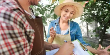 Agricultores analisam documentos e discutem gestão rural em feira ao ar livre, cercados por árvores.