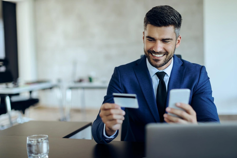Programas do governo para empresas: como aproveitá-los? 17 Empresário sorri ao utilizar cartão de crédito concedido via programas do governo para empresas.