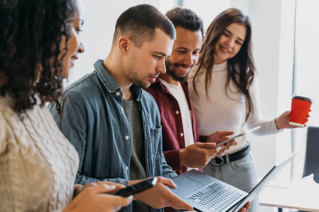 Grupo de jovens usando laptop e smartphones, explorando estratégias no LinkedIn para negócios.