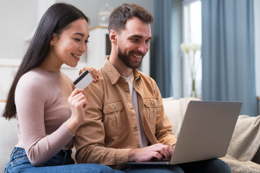 Casal feliz faz compra online com cartão, mostrando que milhas valem dinheiro e geram economia.