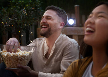 Amigos se divertem assistindo novas séries de 2025 em uma sessão de cinema ao ar livre.