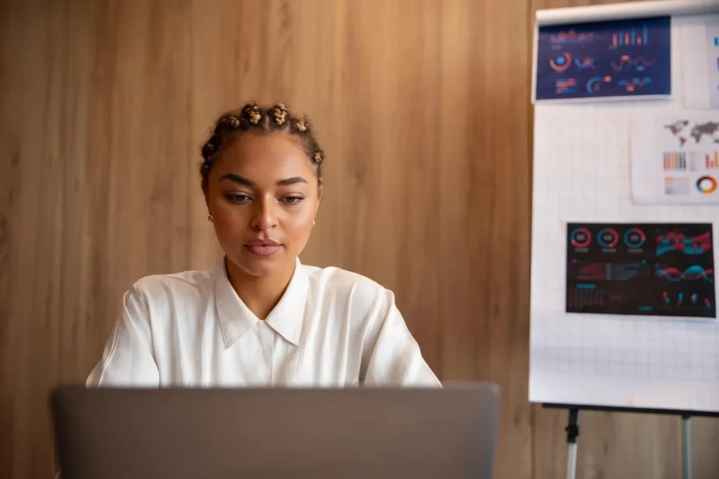 Mulher analisando gráficos financeiros no laptop, avaliando opções de gift card Tesouro Direto.