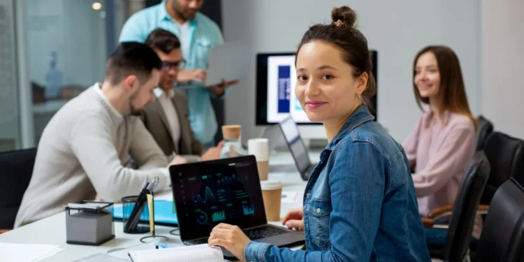 Mercado de trabalho em 2025: as profissões em alta e as habilidades mais demandadas 18 Profissionais se reúnem em sala de trabalho, cada um com seu computador. Representando profissões em alta em 2025.