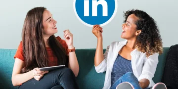 Duas mulheres sorrindo em um sofá, segurando o logo do LinkedIn e discutindo LinkedIn para negócios.
