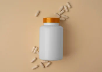 Frasco de produto encapsulado com algumas cápsulas à sua volta. Falando sobre vender encapsulados na internet.