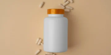 Frasco de produto encapsulado com algumas cápsulas à sua volta. Falando sobre vender encapsulados na internet.