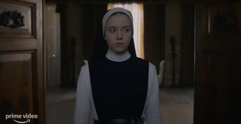 Filmes de suspense psicológico: Freira jovem, com olhar tenso, observa algo à frente em um ambiente sombrio.