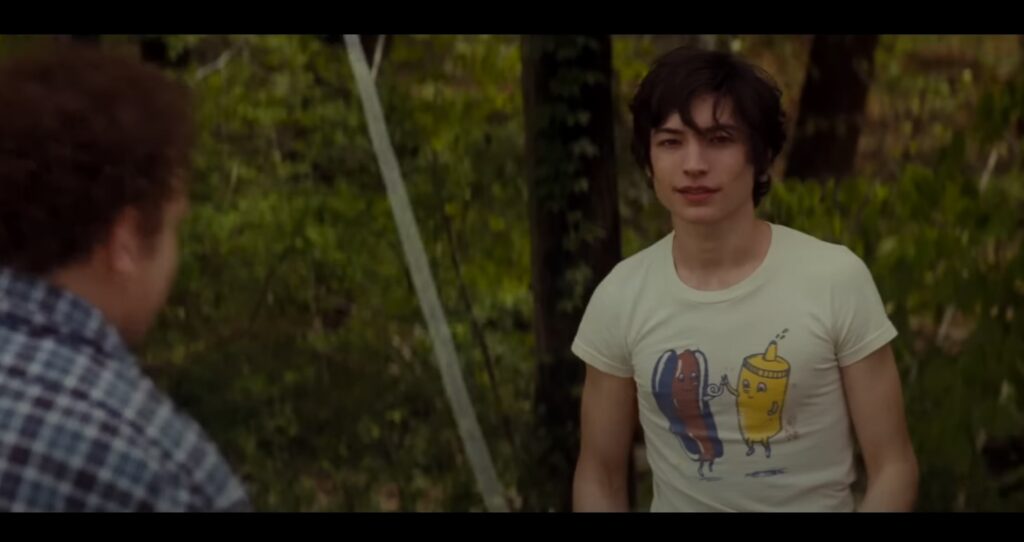 Filmes de suspense psicológico: Jovem de camiseta branca observa algo tenso com expressão intrigante.